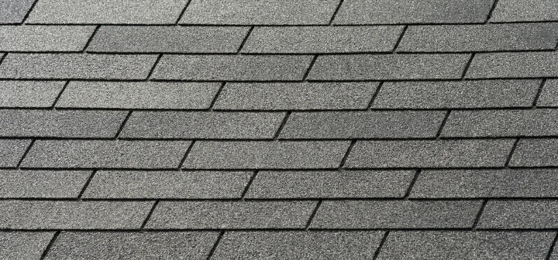 Close-up of flat gray three-tab asphalt shingles in a uniform strip pattern on a residential roof