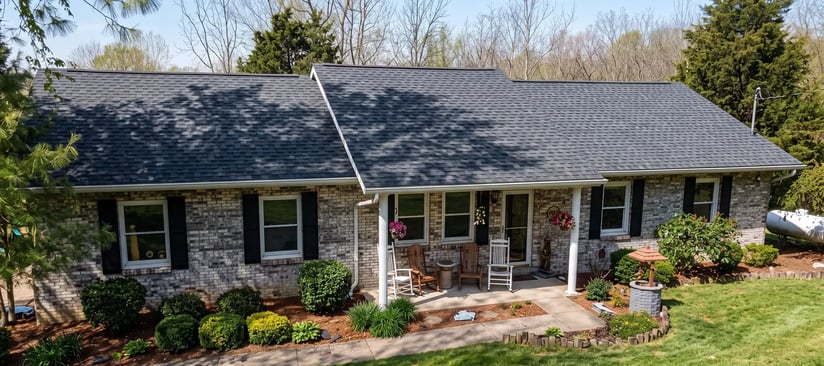 Charcoal architectural asphalt shingles and white gutters on a single-story brick home after roof replacement