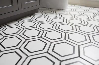 Black and white hexagon floor tile meeting the base of a charcoal vanity after a full replacement
