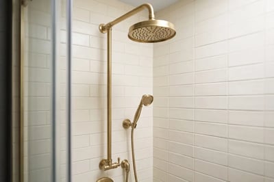 Brass exposed-pipe shower system with rain head and hand shower after a full bathroom replacement