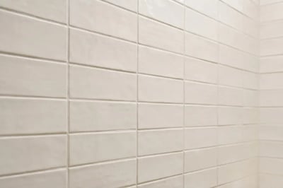 Cream subway tile in a stacked grid with aligned grout joints after a full bathroom replacement