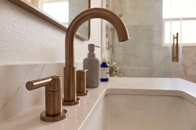 Brushed bronze widespread faucet and lever handles on a quartz vanity top after a bathroom refresh