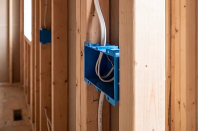 Blue electrical box and white NM cable fastened to a stud during bathroom gut renovation wiring