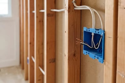 Electrical box and NM cable run through stud framing during bathroom remodel rough-in wiring