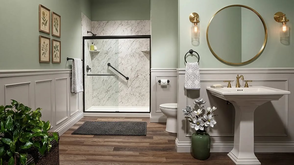 Marble-look shower surround with a black sliding door and pedestal sink after a bathroom remodel — Hybrid Renovations
