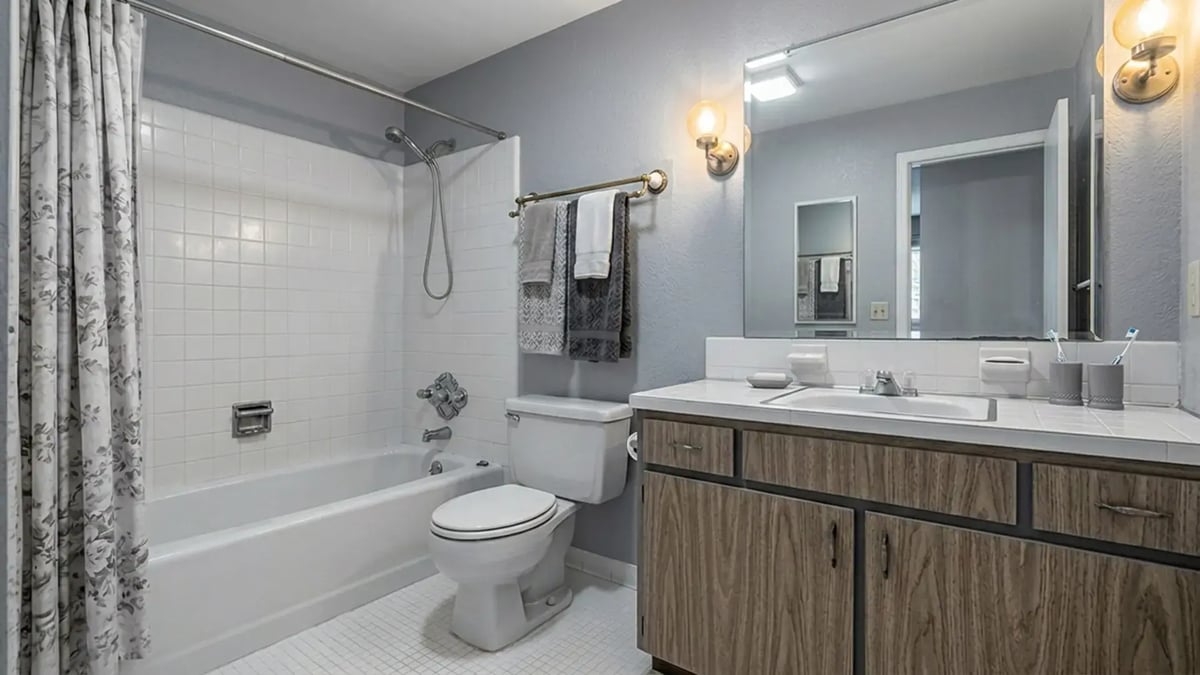 White square tile tub surround, laminate vanity and tiled counter before a bathroom remodel