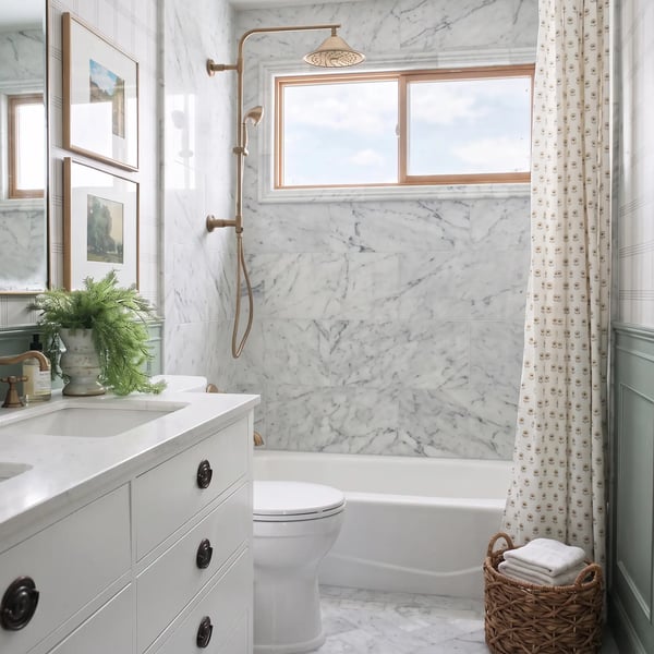 Marble look tile tub surround, brass shower fixtures and white vanity after a full bathroom remodel