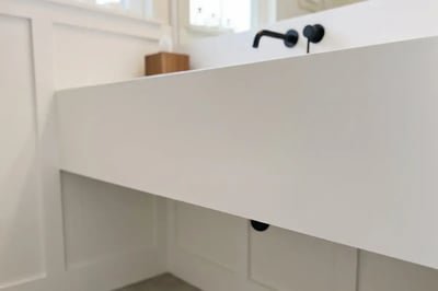Waterfall edge countertop and matte black wall-mount faucet after bathroom remodel vanity install — Hybrid Renovations