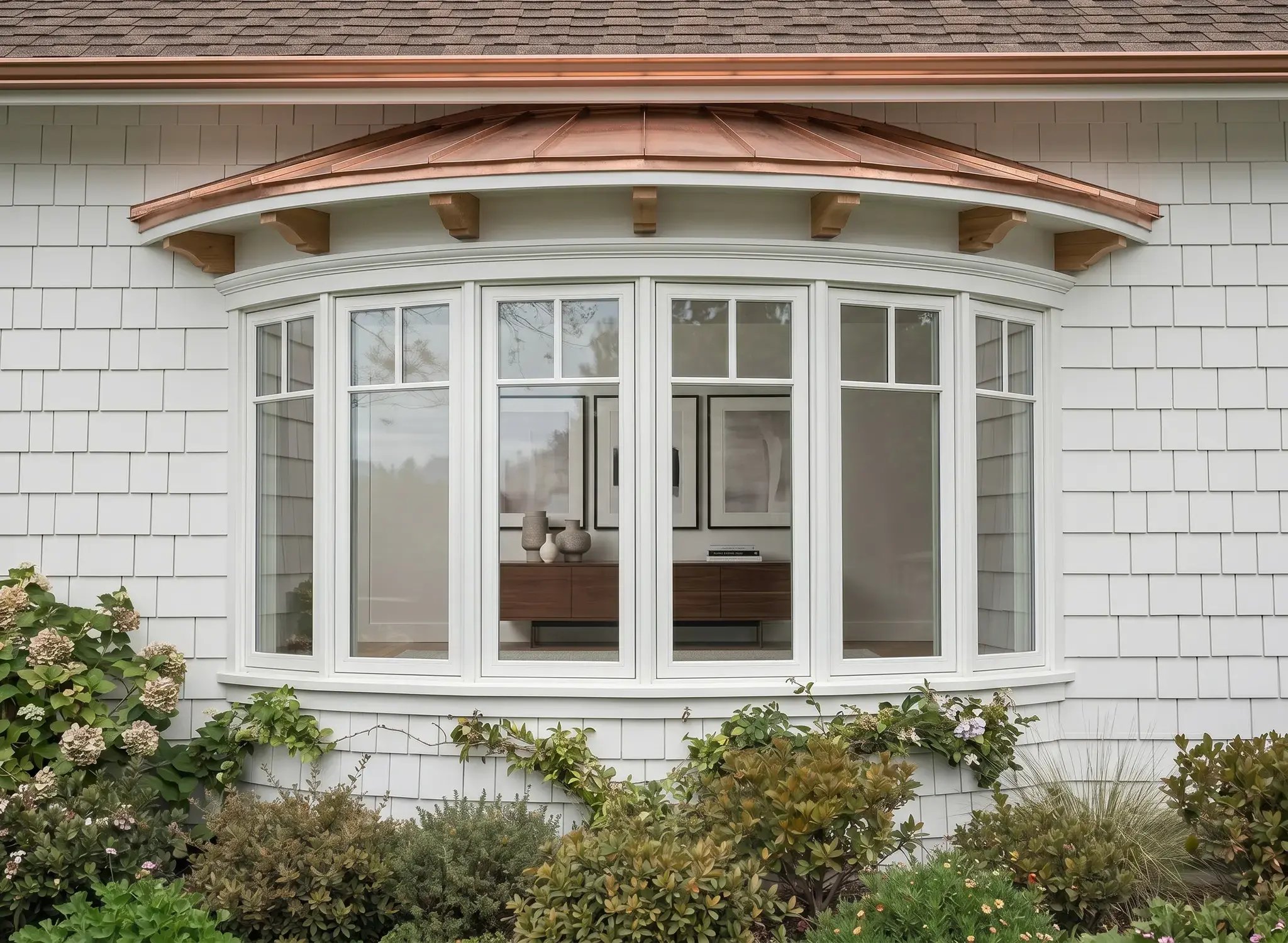 White curved bow window with a copper cap roof after installation on a shingle-sided home — Hybrid Renovations