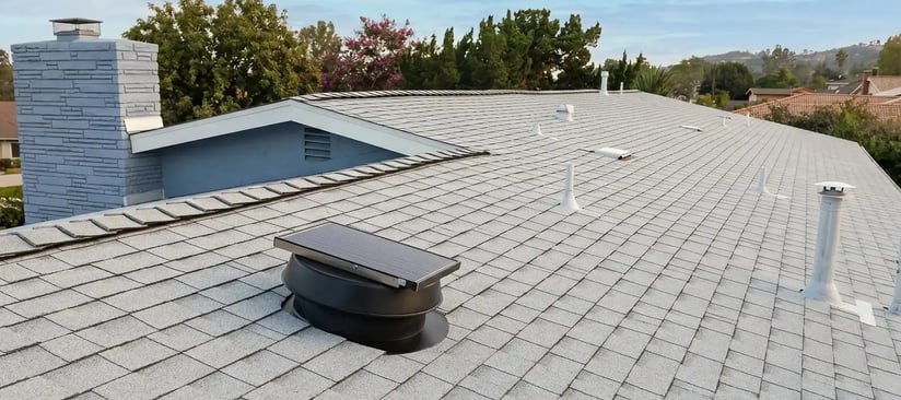 Finished residential cool roof with light-colored architectural shingles and roof vents