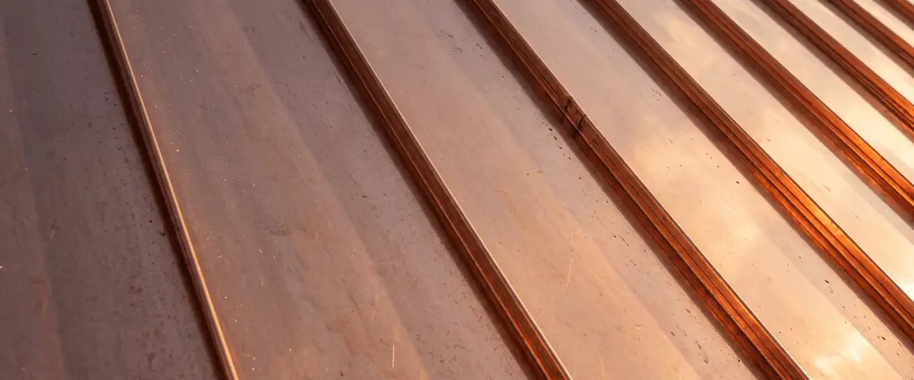 Warm copper standing seam metal roofing finish sample with a bright, reflective surface