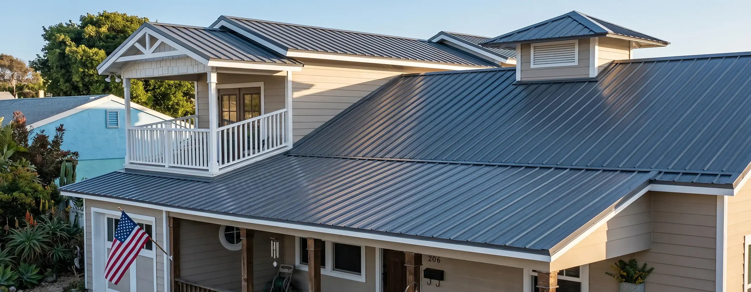 Slate blue corrugated metal roof with cupola and dormer on a two-story coastal home — Hybrid Renovations roofing contractor