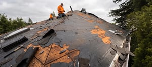Damaged residential roof with torn shingles and exposed roof decking