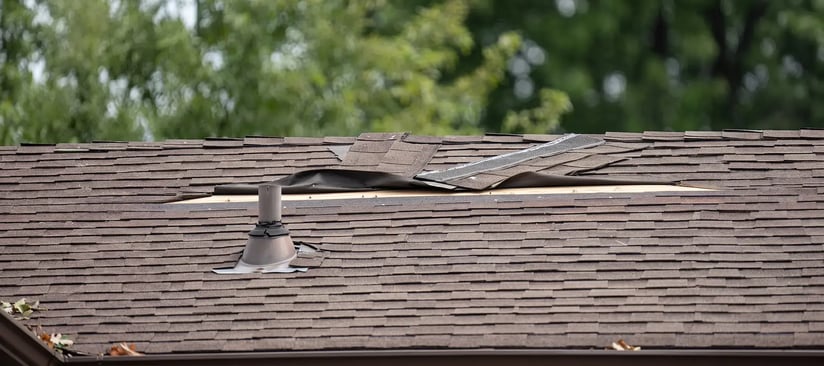 Damaged roof shingles and flashing around a plumbing vent boot