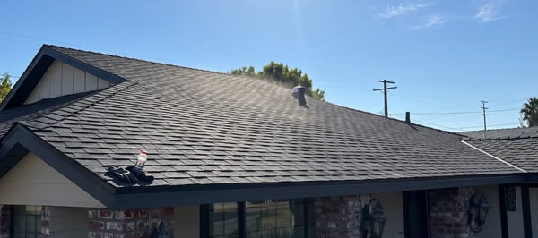 Dark charcoal architectural asphalt shingle roof with a wind turbine attic vent on a single-story home
