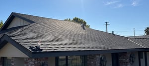 Dark charcoal architectural asphalt shingle roof with a wind turbine attic vent on a single-story home