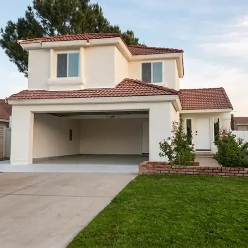 Cream stucco walls and clay tile roof after exterior painting and stucco refresh on two-story home — Hybrid Renovations