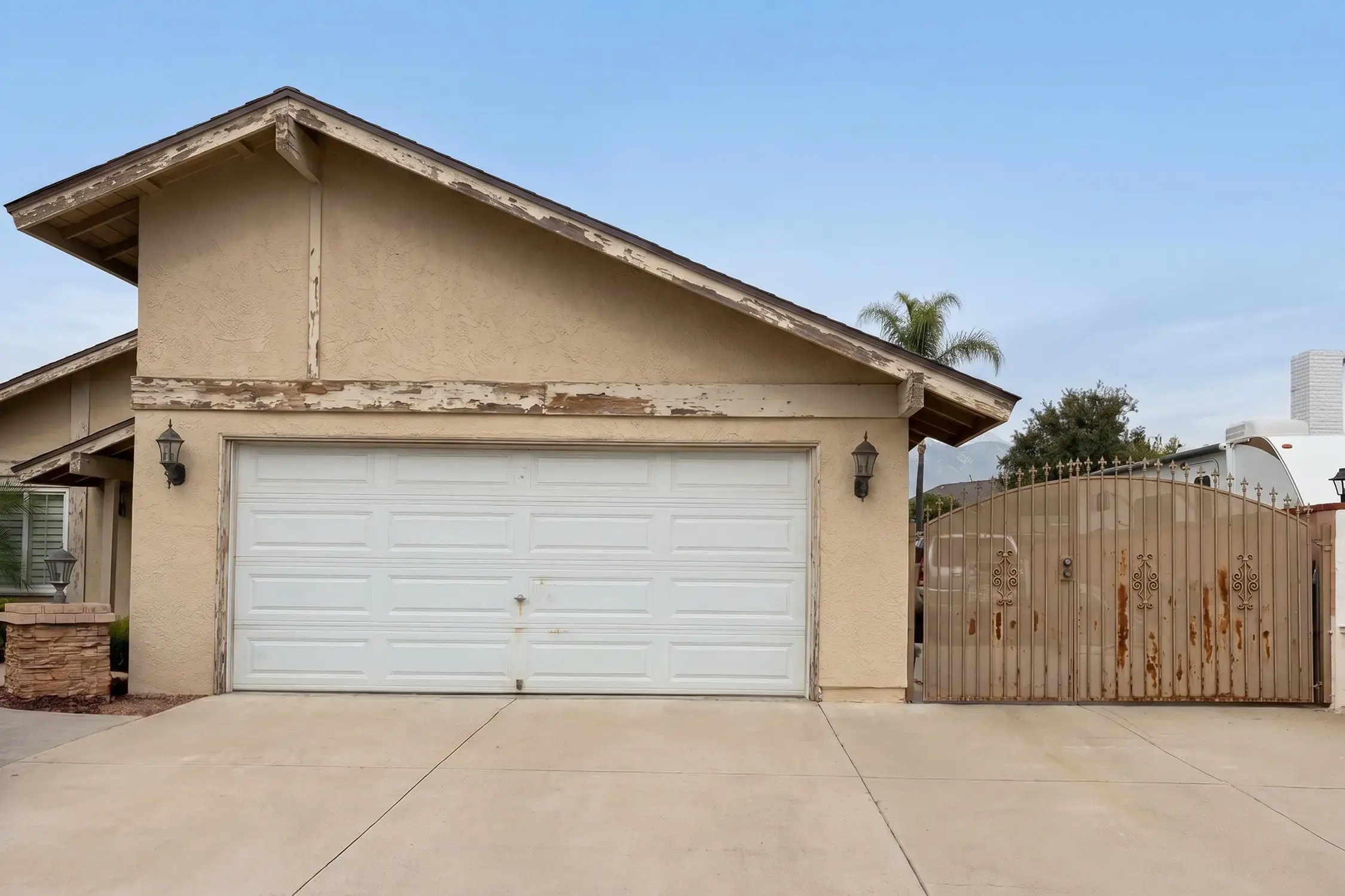 Same garage elevation before the repaint with peeling fascia beams and faded stucco, Ontario