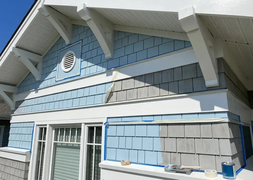 Shingle siding partway through repaint with taped edges during residential exterior painting — Hybrid Renovations