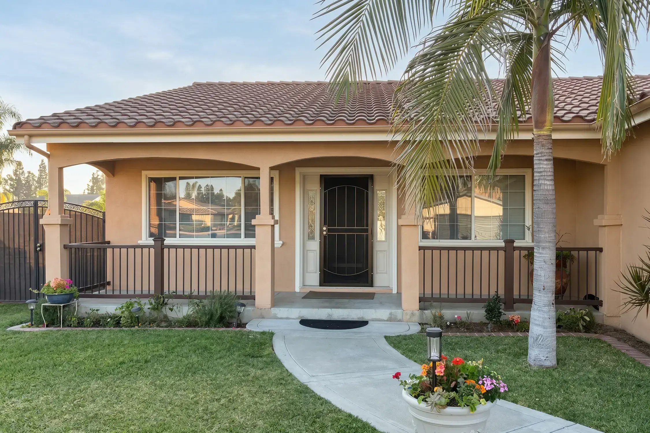 Freshly repainted single-story stucco home with warm tan walls, white trim, a tile roof, and a covered front porch