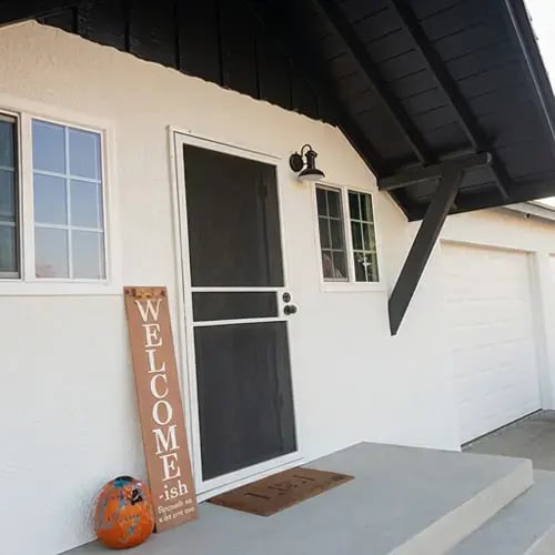 Crisp white stucco walls with dark charcoal trim and gable after exterior repaint and stucco repair on single-family home