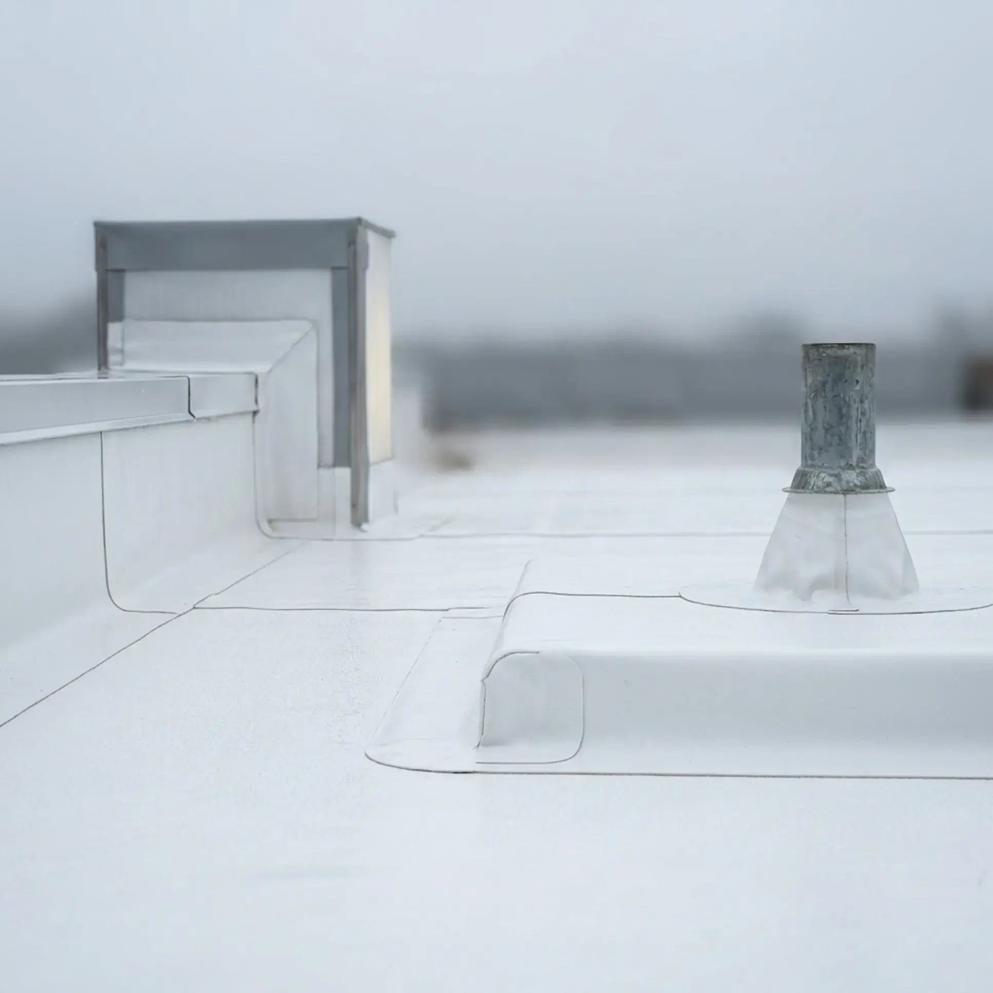 Membrane flashing sealed up a parapet wall and around a vent pipe on a flat roof