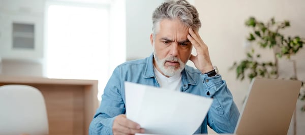 Homeowner reading a letter at a kitchen table with a concerned expression after an insurer roof notice
