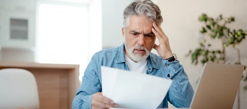 Homeowner reading a letter at a kitchen table with a concerned expression after an insurer roof notice