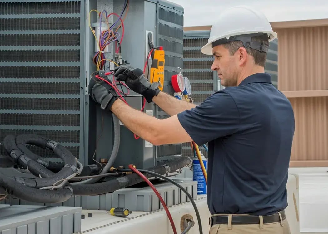 Technician testing the wiring on an outdoor AC condenser unit with meters during HVAC service, Hybrid Renovations