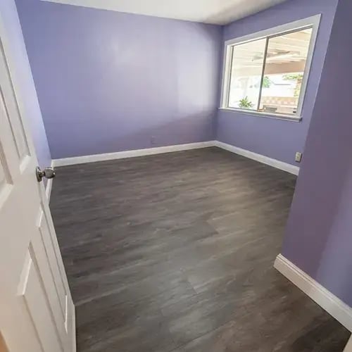Freshly painted lavender bedroom walls with gray vinyl plank flooring after interior painting in single-family home