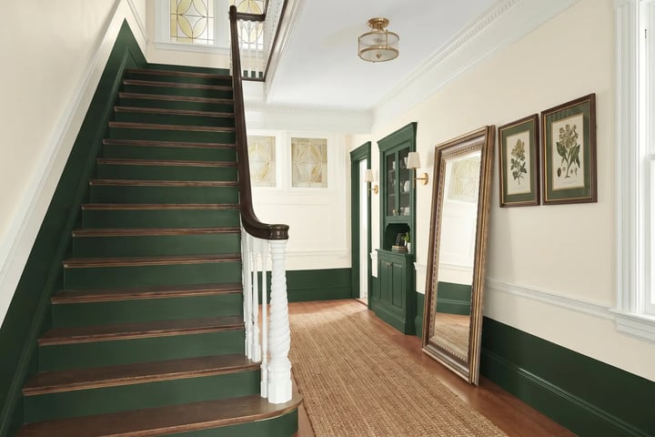 Deep green stair risers and wainscoting against cream hallway walls after interior painting — Hybrid Renovations