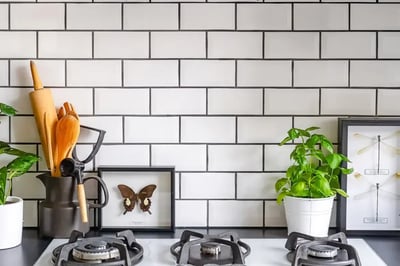 White beveled subway tile backsplash with dark grout behind a gas cooktop in a kitchen