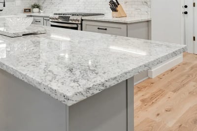 Speckled white and grey granite island countertop with an eased edge in a grey kitchen