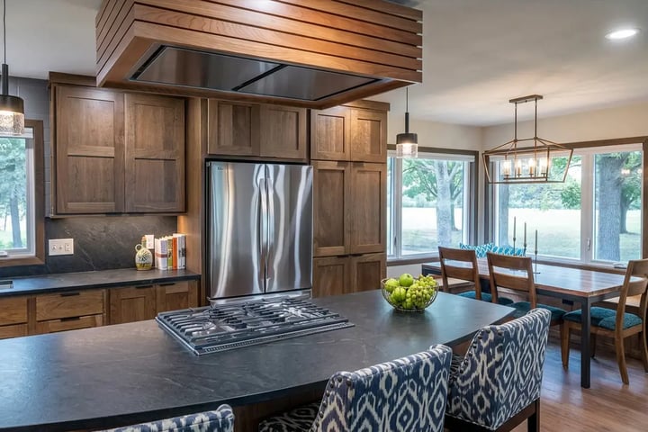 Open plan kitchen after a full gut renovation with walnut cabinets, soapstone island and a slatted wood hood