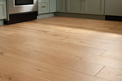 Wide plank white oak flooring running past sage green base cabinets in a remodeled kitchen