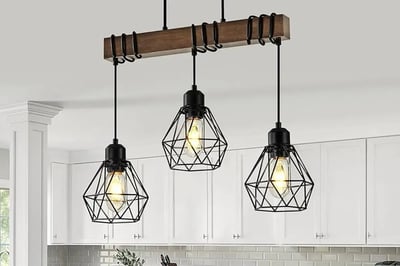 Three-light pendant fixture with a wood beam and black cage shades hung above a kitchen island