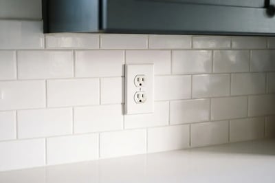 White duplex outlet set into a subway tile backsplash after kitchen electrical work