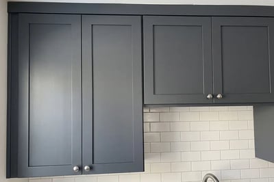 Charcoal shaker upper cabinets at two heights above a white subway tile backsplash