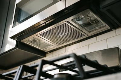 Ventilation grille and light lenses on the underside of an over-range microwave above a gas cooktop