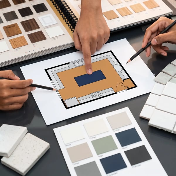 Hands reviewing a kitchen floor plan with cabinet samples and paint chips during a remodel design consultation