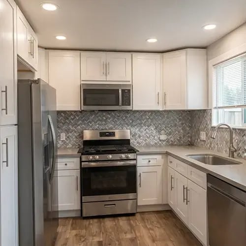 White shaker cabinets and herringbone tile backsplash after residential kitchen remodel — Hybrid Renovations