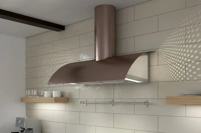 Copper wall-mounted range hood with a ducted chimney above a tiled kitchen wall and open shelves