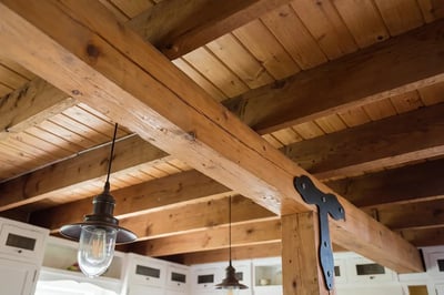 Exposed timber beams and joists with a steel strap at the post connection in an open concept kitchen
