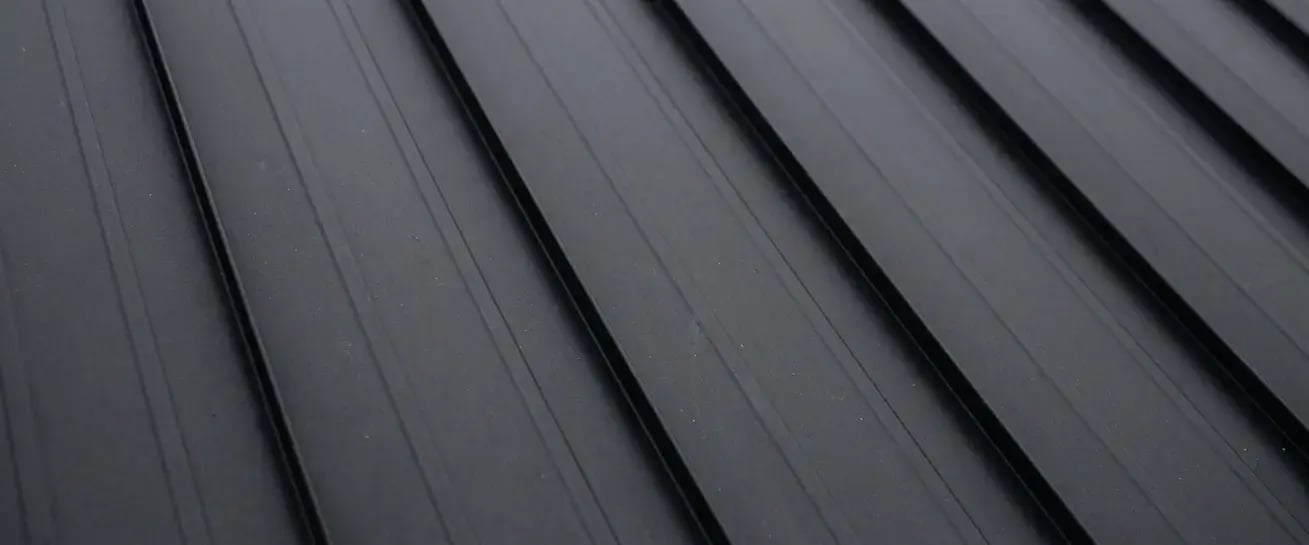 Smooth matte black standing seam metal roofing finish sample with low-sheen ribbed panels by Hybrid Renovations
