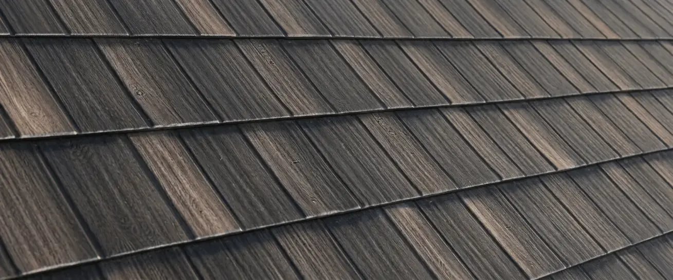 Metallic wood grain print metal roofing finish sample with dark shake-style panels by Hybrid Renovations