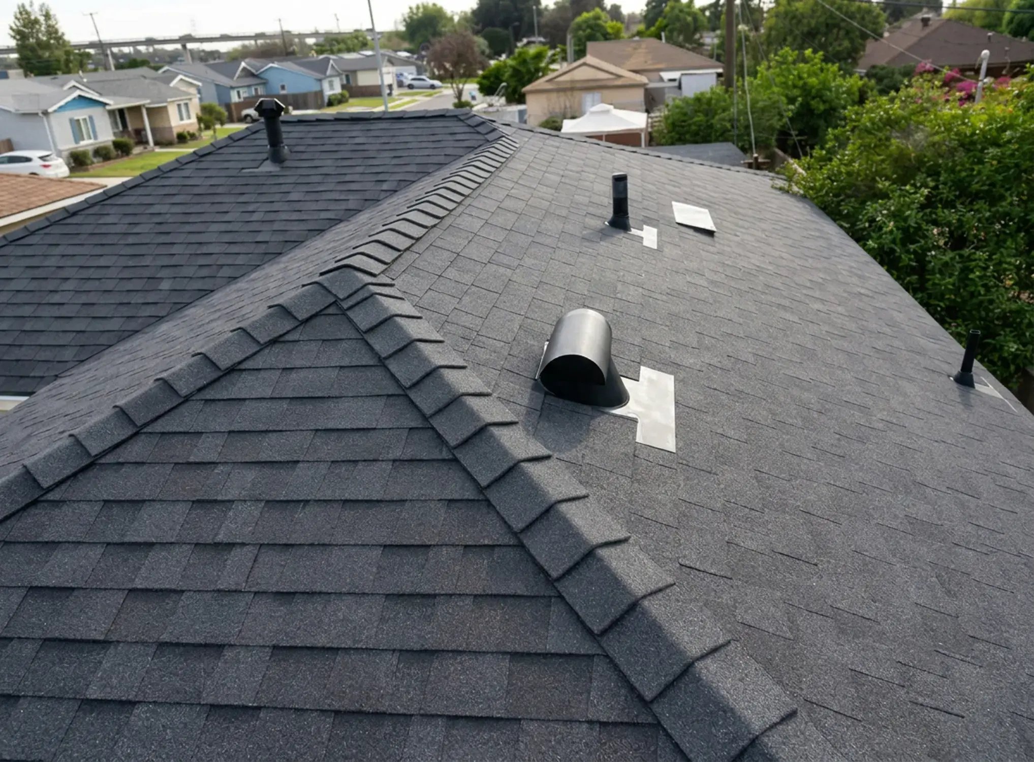 Newly installed charcoal asphalt shingles with new vents after residential roof replacement on a single-family home
