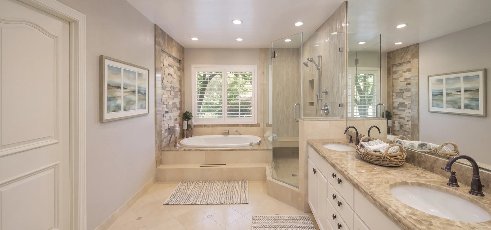 Primary bathroom with a drop-in soaking tub and stone accent wall after a remodel — Hybrid Renovations