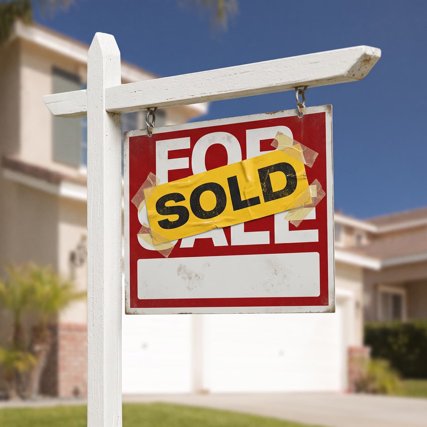 Sold real estate sign in the front yard of a two-story home in a residential neighborhood