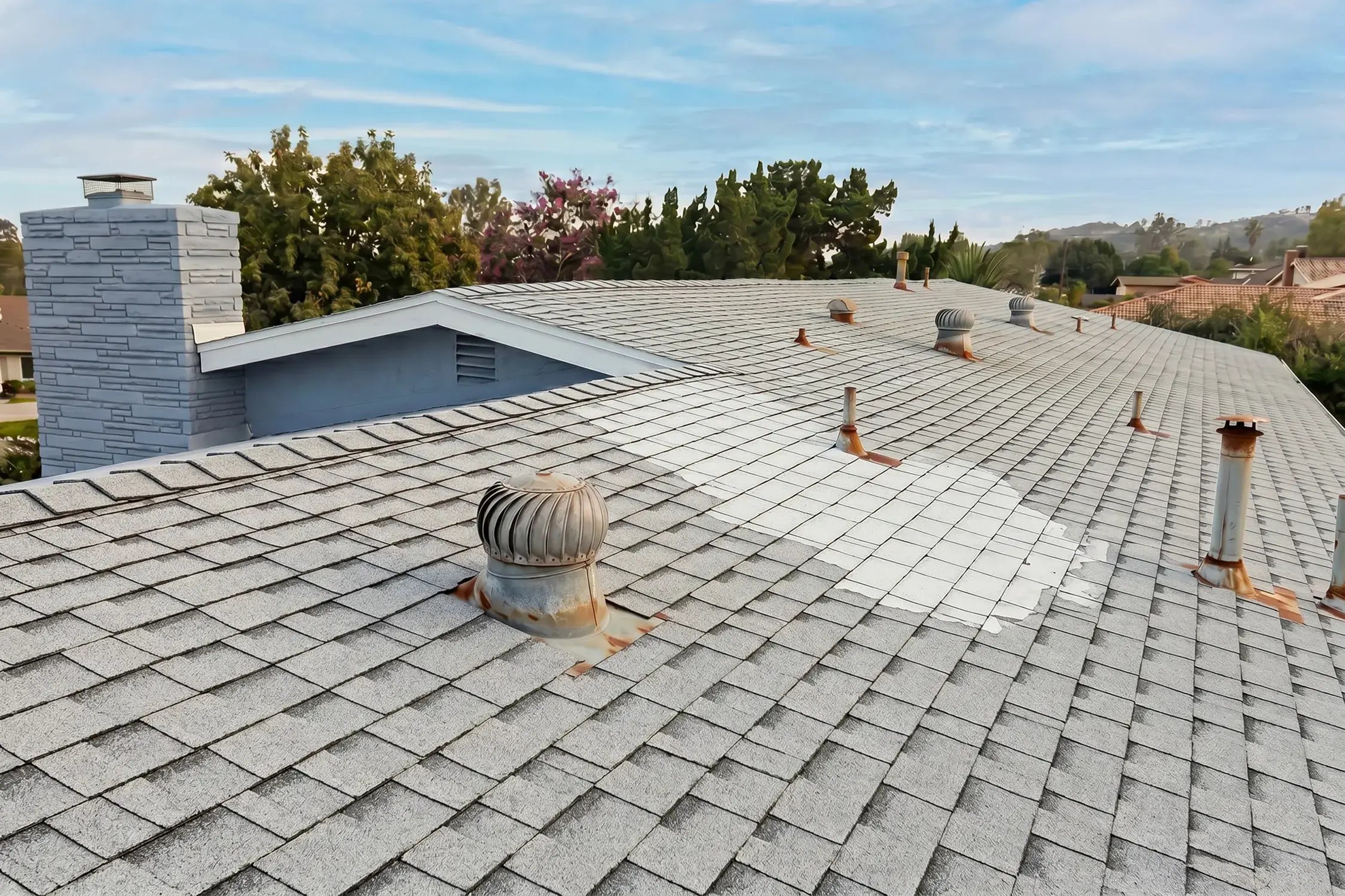 Weathered gray shingle roof with rusted turbine vent and white patch before full tear-off and replacement, Duarte