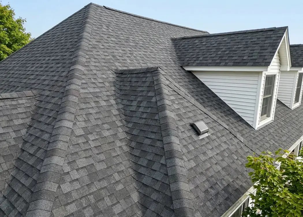 Gray architectural asphalt shingles on a multi-gable single-family home roof after residential roofing work